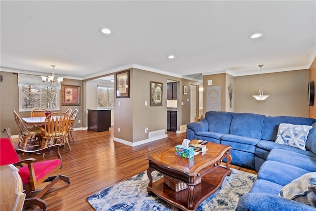 living room featuring baseboards, visible vents, ornamental molding, and wood finished floors