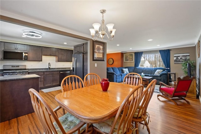 dining area with light wood finished floors, an inviting chandelier, recessed lighting, and crown molding