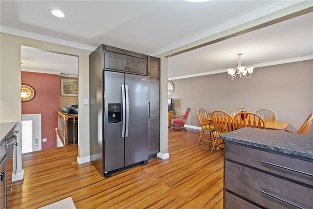 kitchen with appliances with stainless steel finishes, ornamental molding, light wood finished floors, and dark brown cabinets