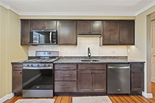 kitchen with dark brown cabinets, stainless steel appliances, a sink, and wood finished floors