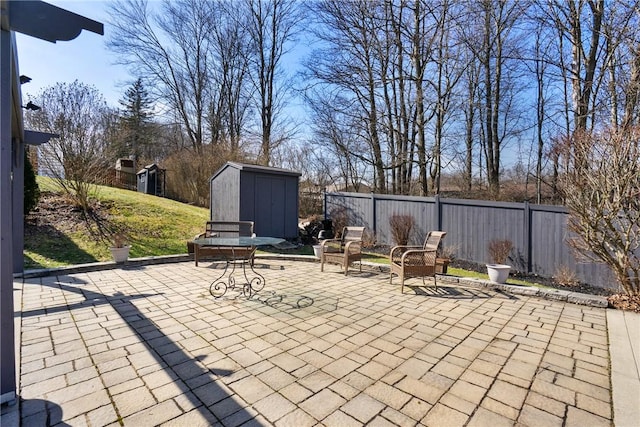 view of patio featuring a shed, a fenced backyard, and an outdoor structure