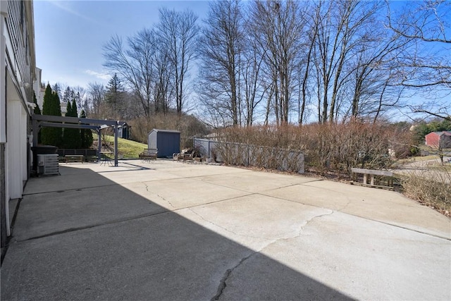 view of patio featuring an outbuilding, a shed, and fence