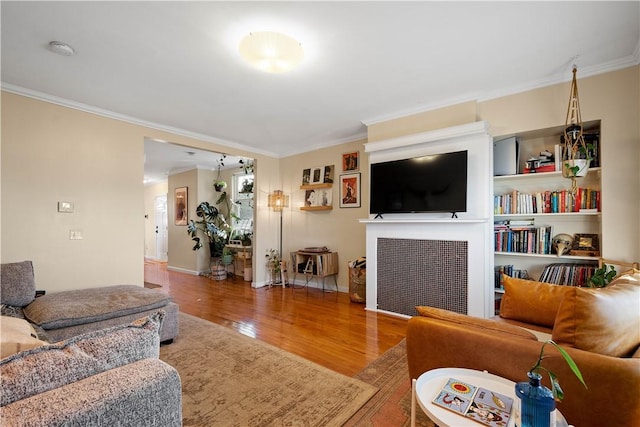 living area featuring crown molding, baseboards, and wood finished floors