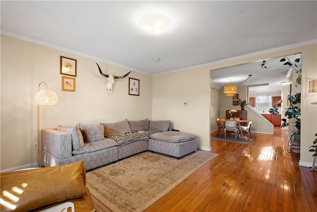 living area with baseboards, hardwood / wood-style flooring, and crown molding