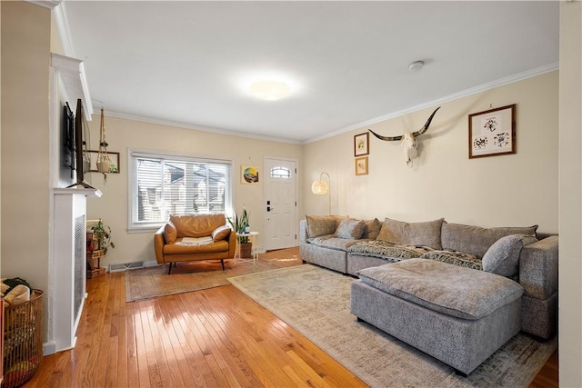 living area with hardwood / wood-style flooring, visible vents, a fireplace, and ornamental molding