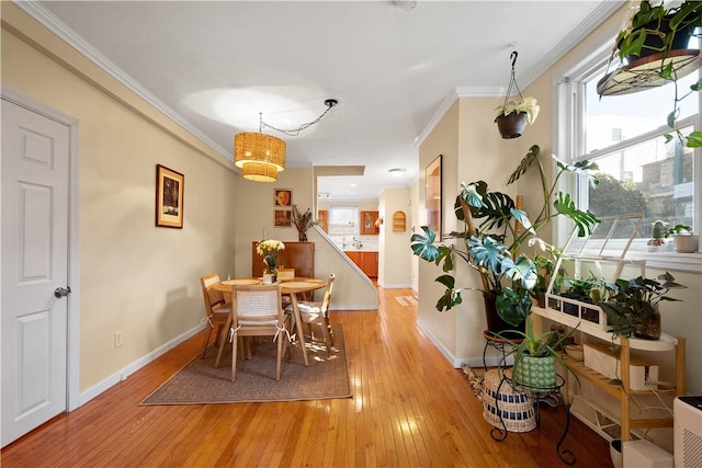 dining space with light wood-style floors, baseboards, and ornamental molding