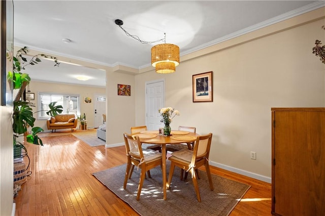 dining room featuring baseboards, crown molding, and light wood finished floors