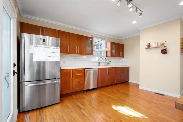 kitchen with stainless steel appliances, brown cabinets, light countertops, and ornamental molding