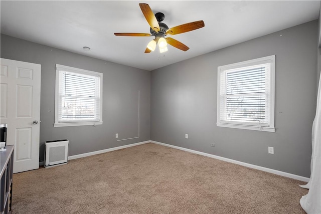 carpeted spare room with a ceiling fan and baseboards