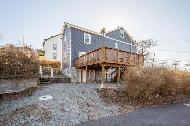 rear view of house with stairs, stone siding, and a wooden deck