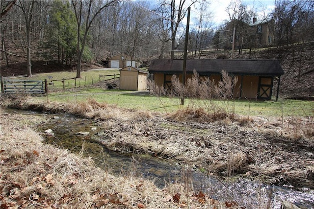 view of yard featuring fence, an outdoor structure, and a storage unit