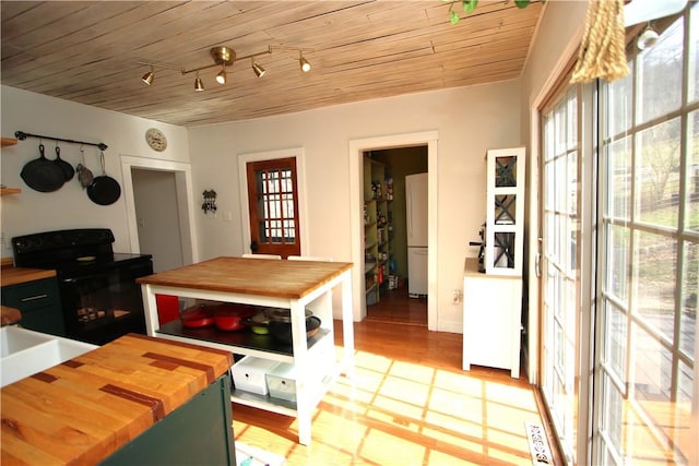 kitchen featuring black range with electric stovetop, freestanding refrigerator, wood ceiling, wood counters, and track lighting