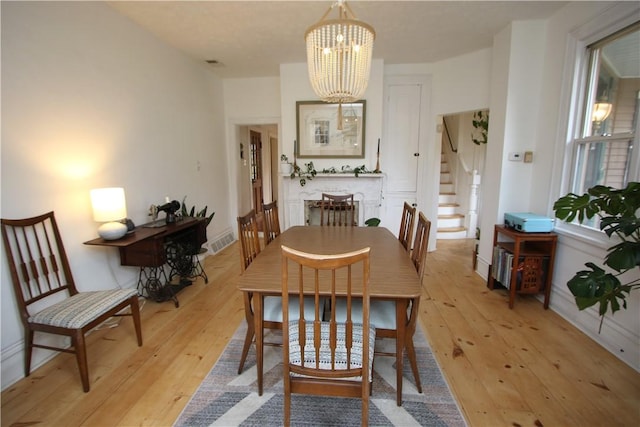 dining area with stairs, visible vents, light wood-style flooring, and an inviting chandelier