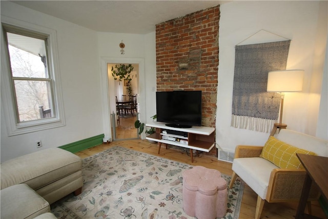 living area with baseboards, visible vents, and wood finished floors