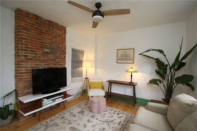 living area featuring baseboards, a ceiling fan, and wood finished floors