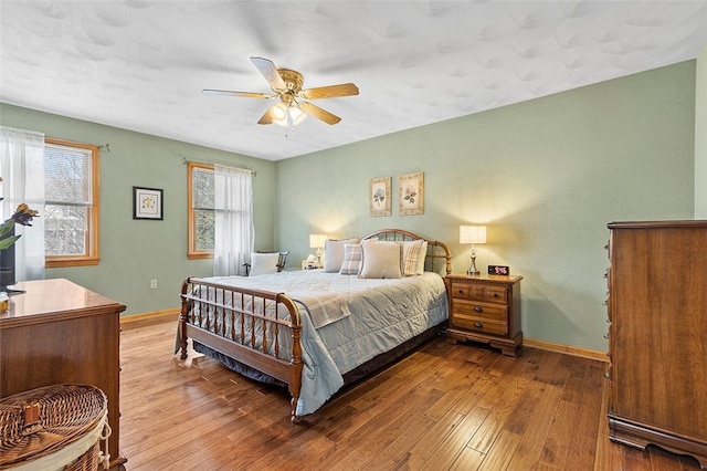 bedroom with wood-type flooring, multiple windows, ceiling fan, and baseboards