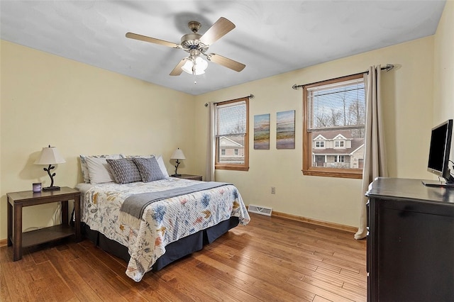 bedroom featuring wood-type flooring, visible vents, ceiling fan, and baseboards