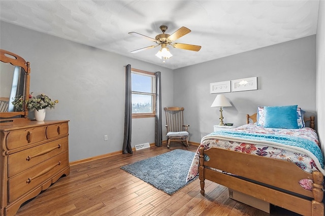 bedroom featuring a ceiling fan, light wood-type flooring, visible vents, and baseboards