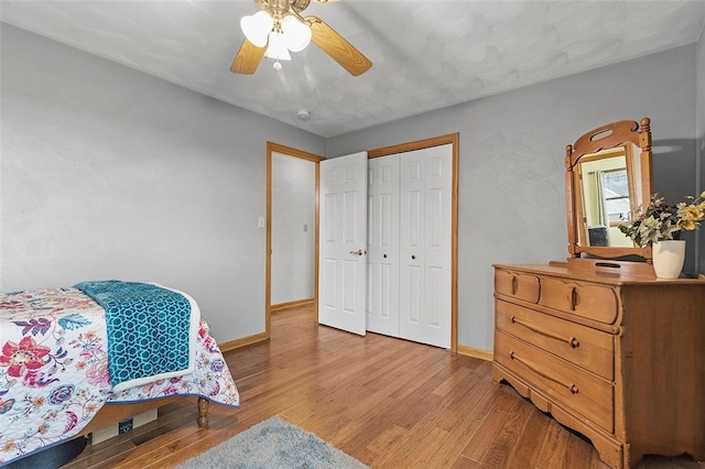 bedroom with light wood-style floors, ceiling fan, baseboards, and a closet