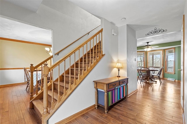 stairs featuring wood-type flooring, baseboards, and a chandelier