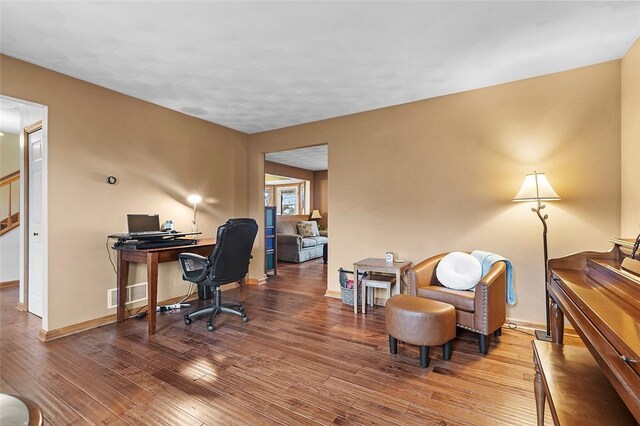 home office with baseboards, visible vents, and hardwood / wood-style floors