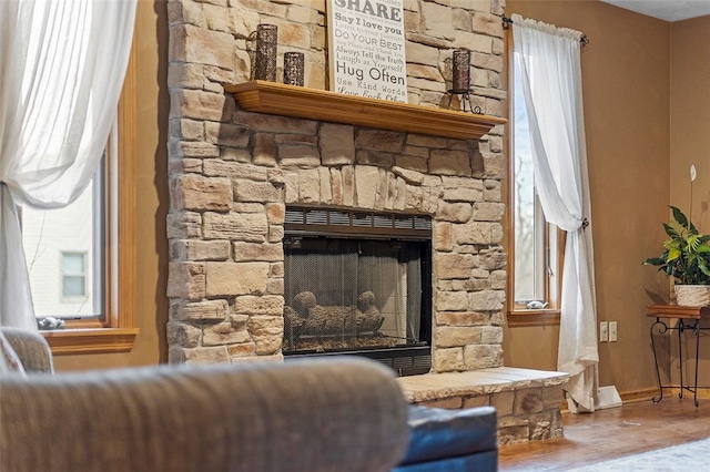 living area featuring a fireplace, wood finished floors, and baseboards