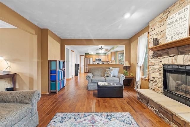 living area featuring a fireplace, hardwood / wood-style flooring, and baseboards