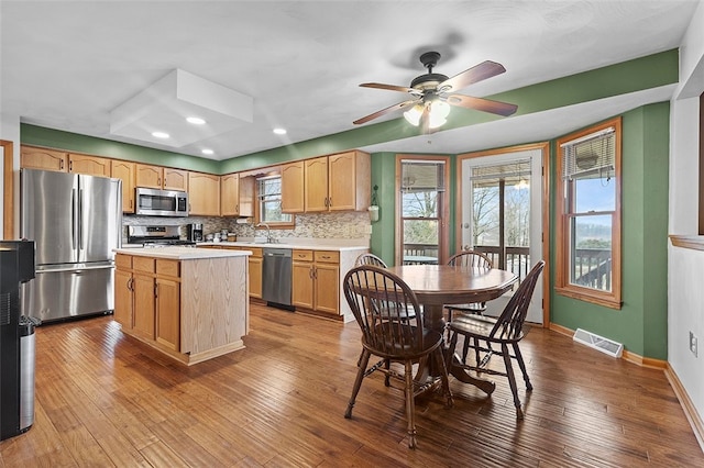 kitchen featuring visible vents, hardwood / wood-style flooring, appliances with stainless steel finishes, light countertops, and backsplash