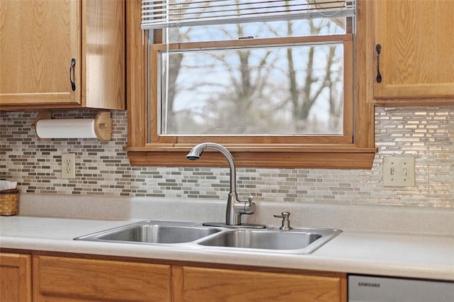 kitchen with dishwashing machine, a sink, light countertops, and decorative backsplash