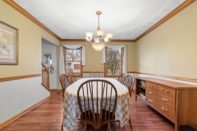 dining area featuring ornamental molding, dark wood-style flooring, baseboards, and an inviting chandelier