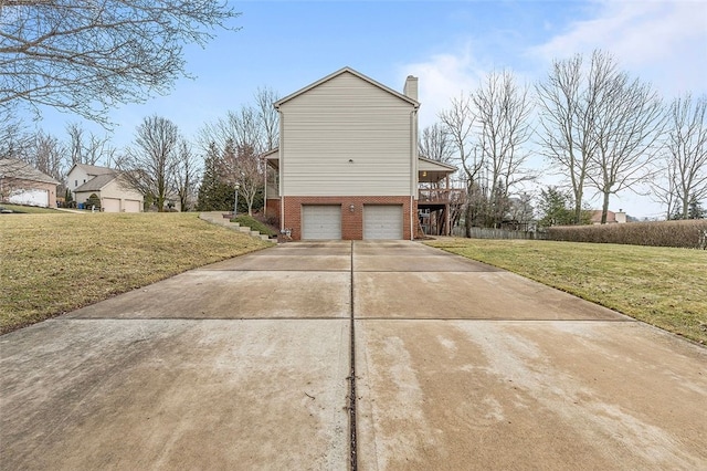 view of side of property featuring a garage, brick siding, driveway, a yard, and a chimney