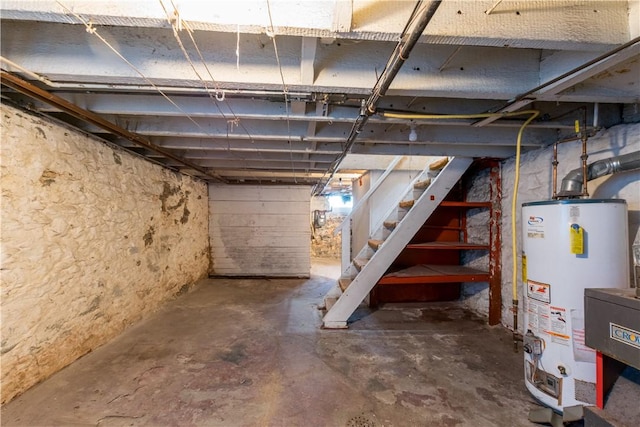 unfinished below grade area featuring gas water heater and stairs