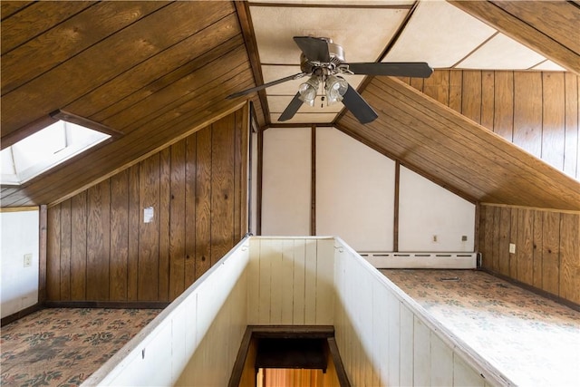 additional living space featuring lofted ceiling with skylight and wood walls