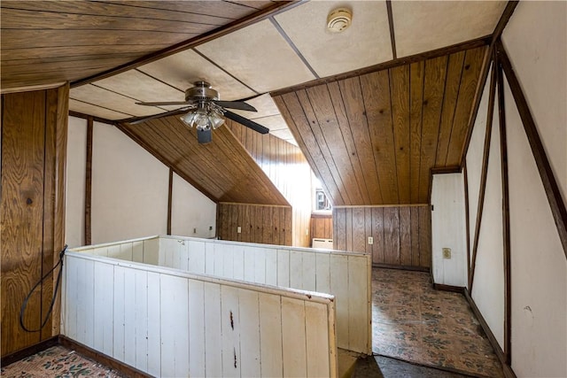 additional living space with wooden ceiling, wooden walls, vaulted ceiling, and a ceiling fan