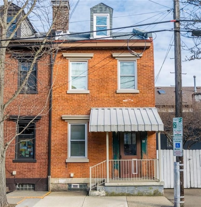 view of front of home featuring a chimney, fence, and brick siding