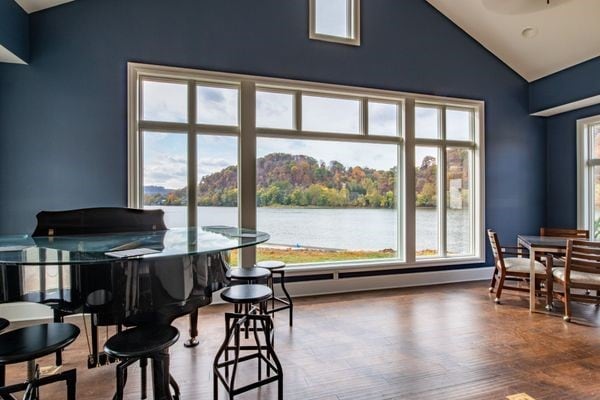 dining space with a water view, vaulted ceiling, wood finished floors, and baseboard heating