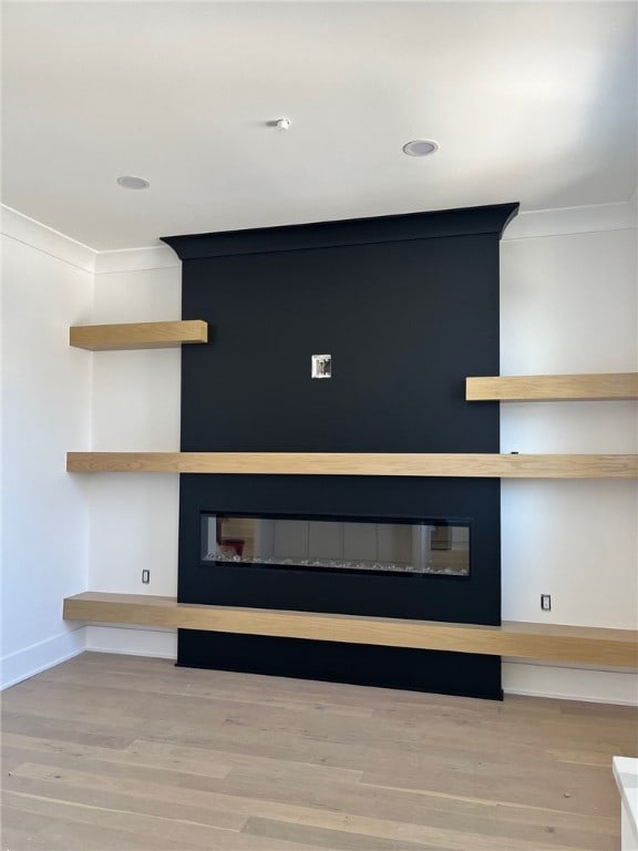 room details with ornamental molding, baseboards, a fireplace, and wood finished floors