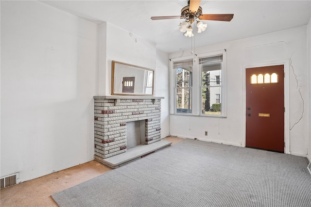 carpeted living area with a brick fireplace, ceiling fan, and visible vents