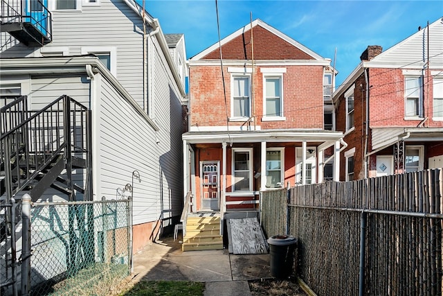 rear view of property featuring entry steps, brick siding, and a fenced backyard