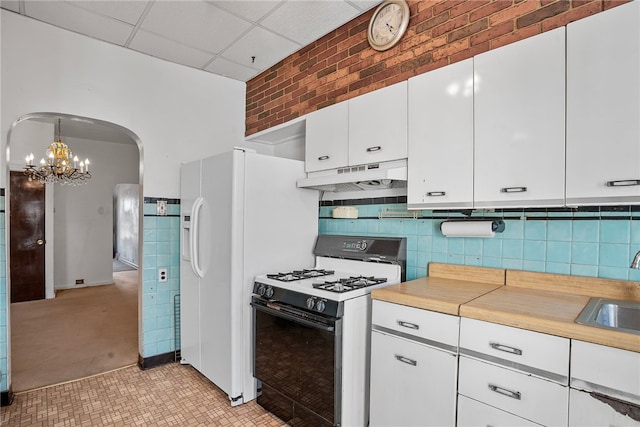 kitchen with arched walkways, white gas stove, light countertops, white cabinetry, and under cabinet range hood