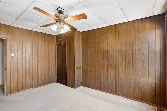 spare room with carpet floors, a paneled ceiling, visible vents, and wood walls