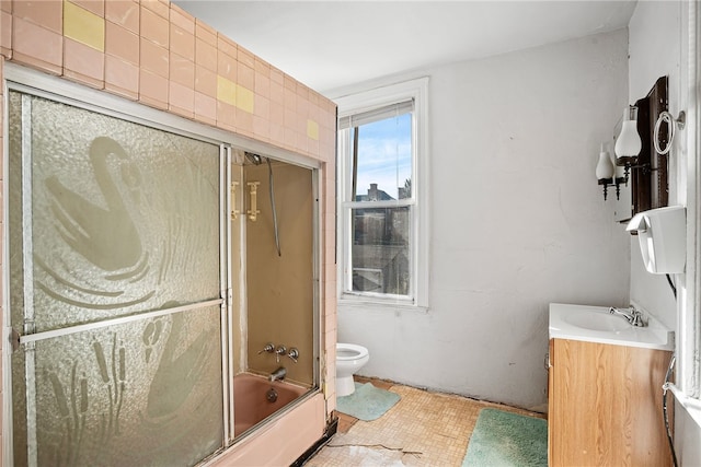 bathroom featuring toilet, shower / bath combination with glass door, and vanity