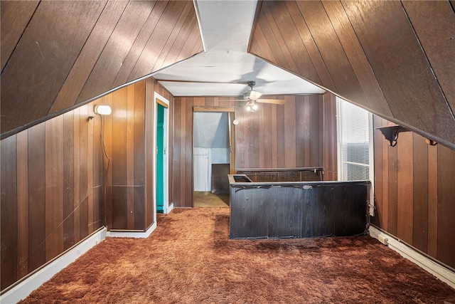 additional living space with a ceiling fan, carpet flooring, and wooden walls