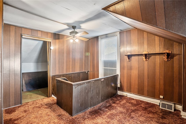 interior space featuring carpet, wooden walls, visible vents, and a ceiling fan