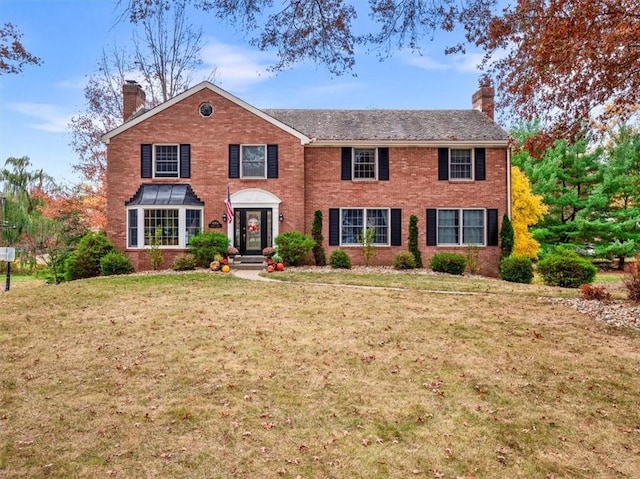 colonial home featuring brick siding and a chimney