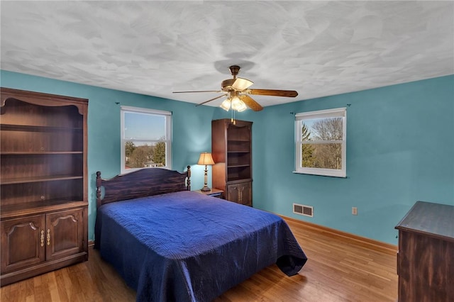 bedroom featuring multiple windows, visible vents, and wood finished floors