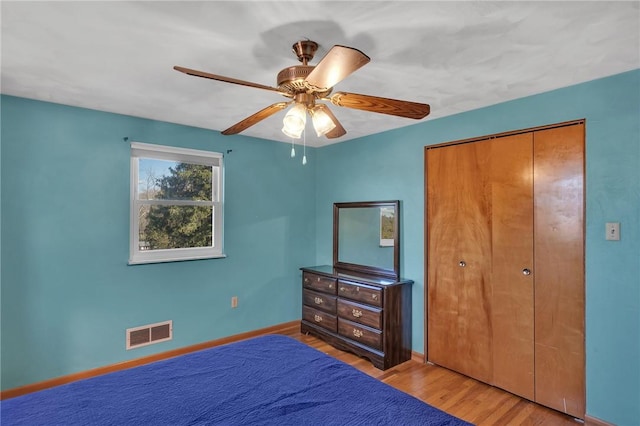 bedroom with a closet, visible vents, ceiling fan, wood finished floors, and baseboards