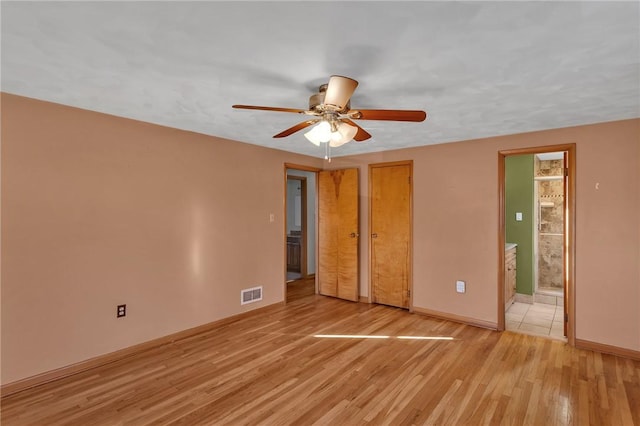 unfurnished bedroom with a ceiling fan, visible vents, baseboards, light wood-type flooring, and ensuite bath