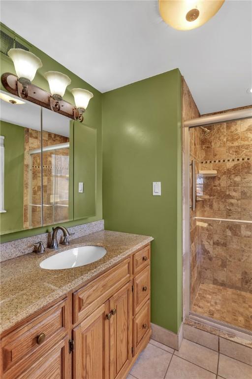 bathroom featuring a stall shower, tile patterned flooring, and vanity