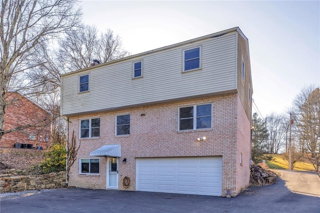 view of front of home featuring an attached garage, aphalt driveway, and brick siding